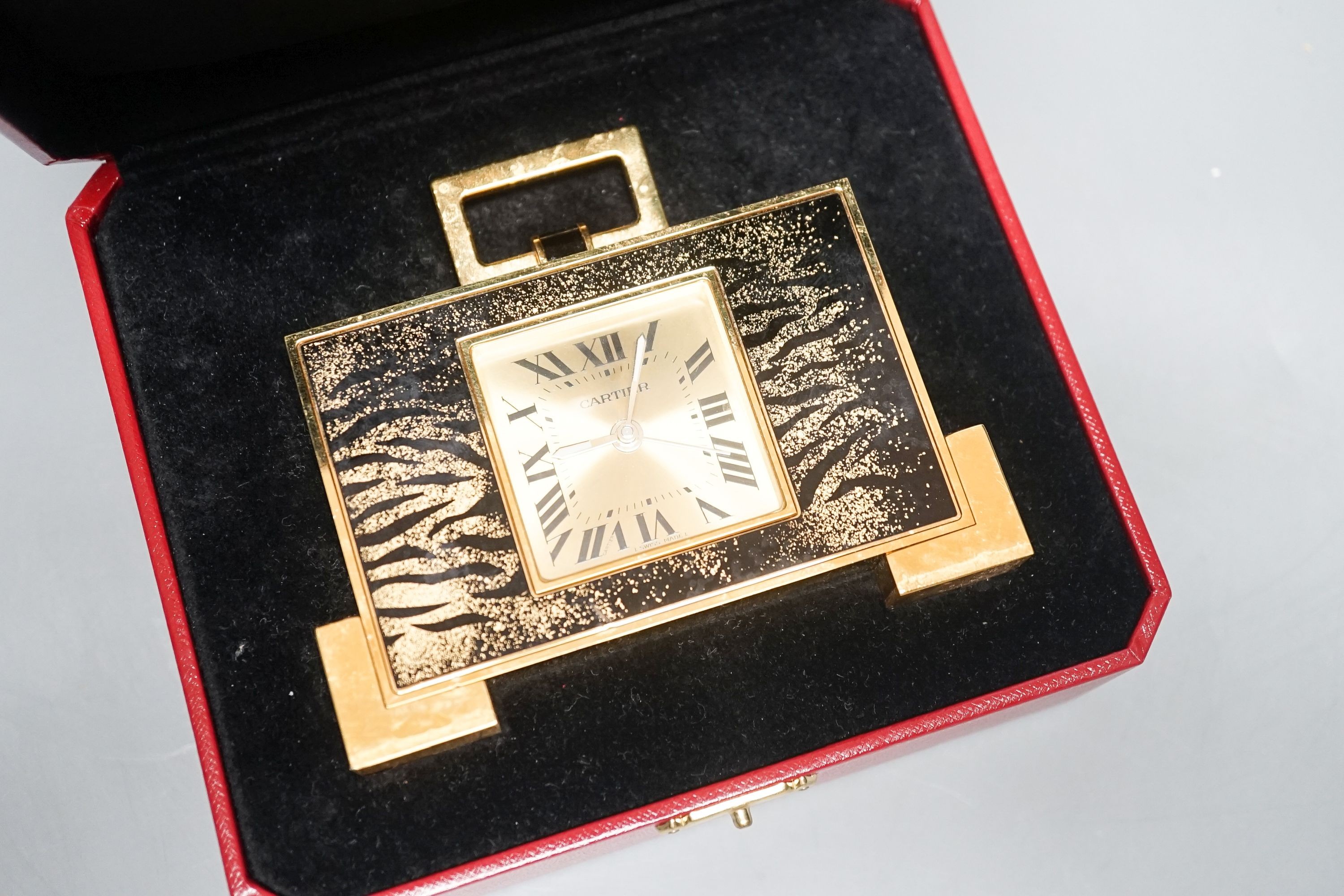 A cased Cartier gilt metal travelling clock, 10.5 cm wide, with certificate booklet